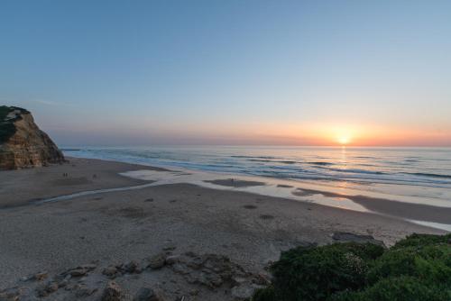 - une plage au coucher du soleil sur l'océan dans l'établissement Eco Soul Ericeira Guesthouse - Adults Only, à Ericeira