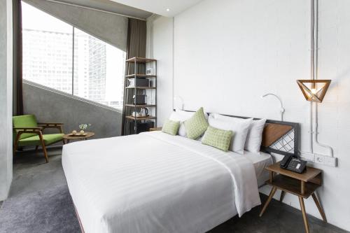 - une chambre blanche avec un grand lit et une chaise dans l'établissement Janevalla Bandung, à Bandung