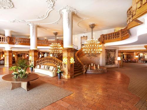 eine große Lobby mit einer Treppe und Kronleuchtern in der Unterkunft Interalpen-Hotel Tyrol in Seefeld in Tirol