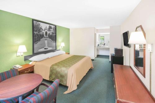 um quarto de hotel com uma cama, uma mesa e cadeiras em Super 8 by Wyndham Mobile em Mobile