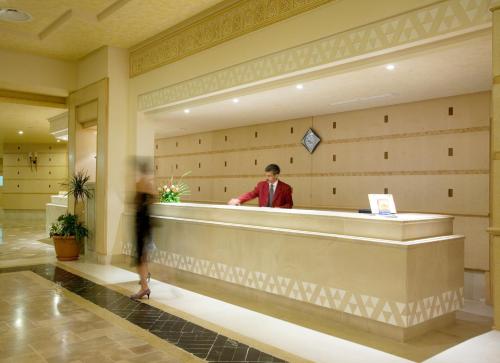 a man standing at a counter in a lobby at El Mouradi Tozeur in Tozeur