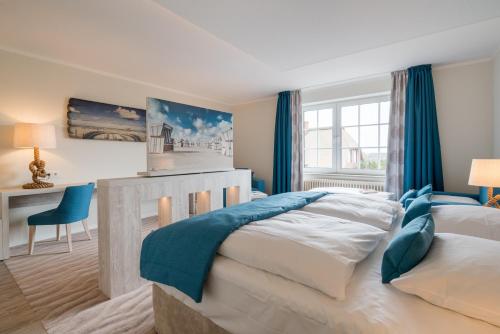 una camera da letto con un grande letto con tende blu di Hotel Garni Kölfhamm a Sankt Peter-Ording