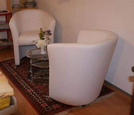 a living room with two white chairs and a glass table at Studio in Chasa Quirin in Zernez