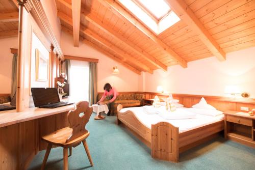 a woman in a room with a bed and a laptop at Villa Rier in Siusi