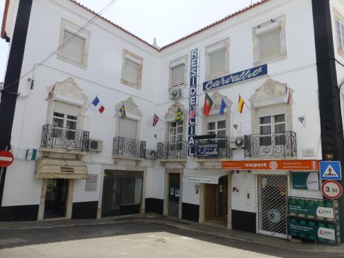 een wit gebouw met vlaggen op de balkons bij Residencial Carvalho in Estremoz