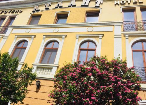 ein gelbes Gebäude mit Blumen davor in der Unterkunft Atlant Hotel in Uschhorod