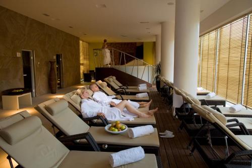 two people sitting on chairs in a living room at Hotel Garden Istra Plava Laguna in Umag