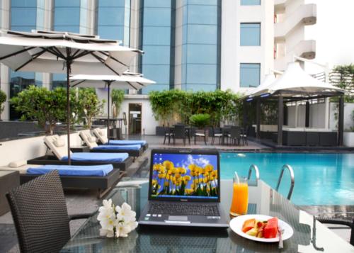 a laptop sitting on a glass table next to a swimming pool at The Golkonda Hotel in Hyderabad