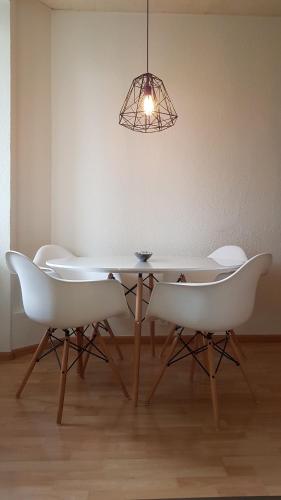 une table à manger avec des chaises blanches et un meuble lumineux dans l'établissement Basel Charme Apartments, à Bâle