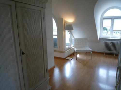 ein Wohnzimmer mit einem weißen Stuhl und 2 Fenstern in der Unterkunft Maisonette am Belchen in Bad Krozingen