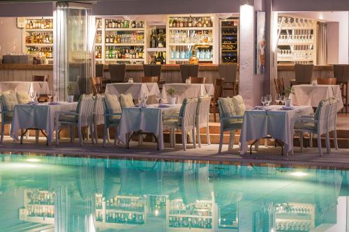 een restaurant met tafels en stoelen naast een zwembad bij La Piscine Art Hotel, Philian Hotels and Resorts in Skiathos-stad