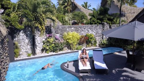 Eine Frau im Bikini sitzt neben einem Pool. in der Unterkunft Aitutaki Escape in Arutanga