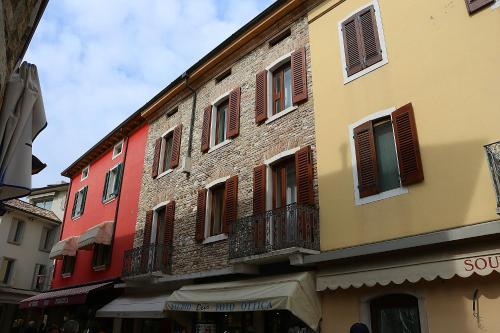 um edifício de tijolos alto com janelas numa rua em Aurora Sirmione Appartamenti em Sirmione