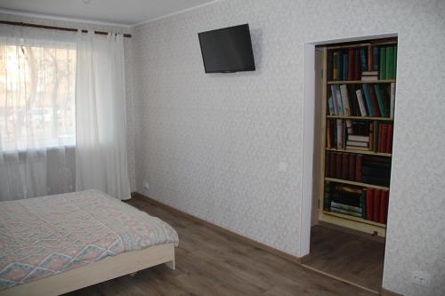 um quarto com uma cama e uma estante de livros com livros em Современная 1-комнатная квартира em Carcóvia