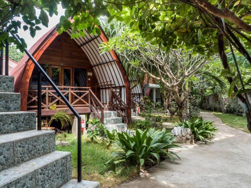 una casa con techo curvado y escaleras en un jardín en Gili Turtle Beach Resort, en Gili Trawangan