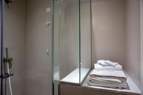 a bathroom with a glass shower and towels on a counter at Apollon Library Suites in Nafpaktos