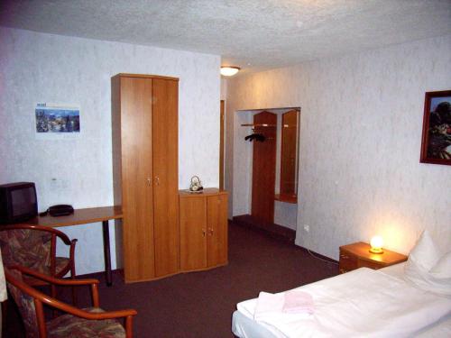 een hotelkamer met een bed, een bureau en een kast bij Gaststätte & Pension Jiedlitz in Burkau