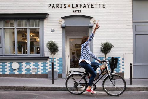 uma mulher a andar de bicicleta com a mão no ar em Hôtel Paris La Fayette em Paris