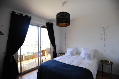 een slaapkamer met een bed en een raam met een balkon bij T2 Terrasse Vue Mer - Route des Sanguinaires in Ajaccio