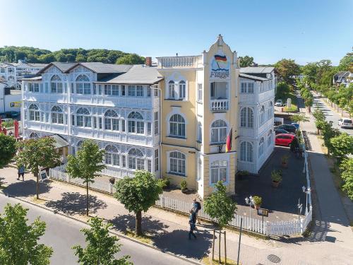 un grand bâtiment jaune et blanc dans une rue de la ville dans l'établissement Hotel Deutsche Flagge, à Binz