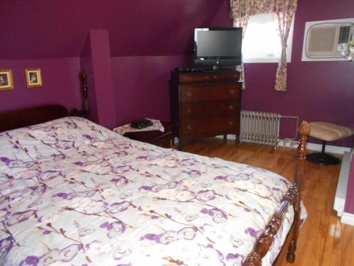 una camera con letto e parete viola di Le Gîte De La Sagouine a Bouctouche