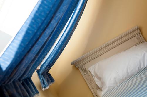 a bed with a blue curtain next to a window at Babiččina Zahrada Penzion & Restaurant in Pruhonice