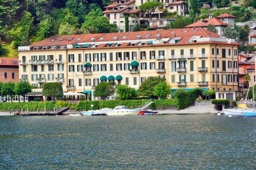 un grande edificio accanto a un bacino idrico con barche di Grand Hotel Menaggio a Menaggio