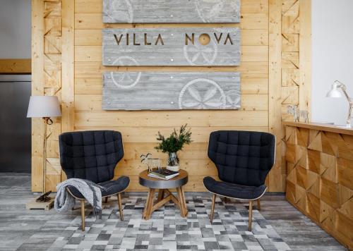 twee stoelen en een tafel in een kamer met een houten muur bij Villa Nova in Zakopane