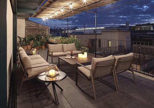 eine Terrasse mit Stühlen und Tischen auf dem Balkon in der Unterkunft Casa Camper Barcelona in Barcelona