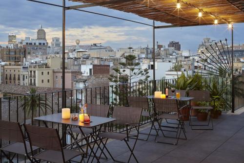 eine Terrasse mit Tischen und Stühlen auf dem Balkon in der Unterkunft Casa Camper Barcelona in Barcelona