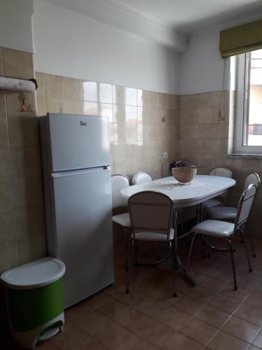 a kitchen with a refrigerator and a table and chairs at Apartamento 300 metros do SANTUÁRIO DE FÁTIMA T4 in Fátima