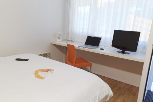 een slaapkamer met een bed en een bureau met een computer bij Premiere Classe Poitiers Futuroscope - Chasseneuil in Chasseneuil-du-Poitou