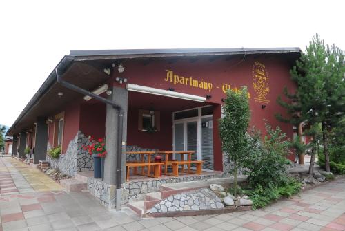 a red building with a wooden table in front of it at Selfness Rožňava in Rožňava