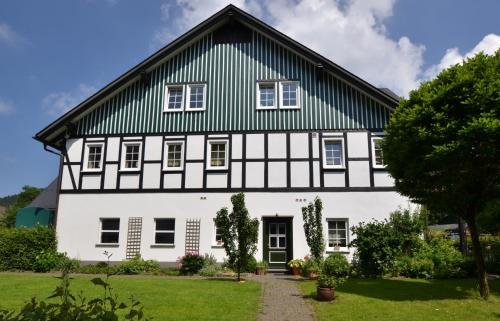 une maison blanche et noire avec un toit vert dans l'établissement Feldmann-Schütte, à Schmallenberg