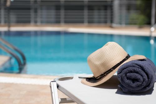 un cappello seduto su una panchina accanto a una piscina di Dimamiel Malia Inn a Mália