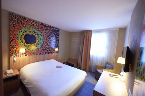 ibis Styles Cholet في شوليه: غرفه فندقيه سرير ابيض ونافذه