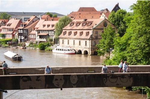 um grupo de pessoas andando em uma ponte sobre um rio em Rathausschänke em Bamberg