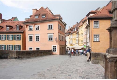 um grupo de pessoas andando por uma rua com edifícios em Rathausschänke em Bamberg