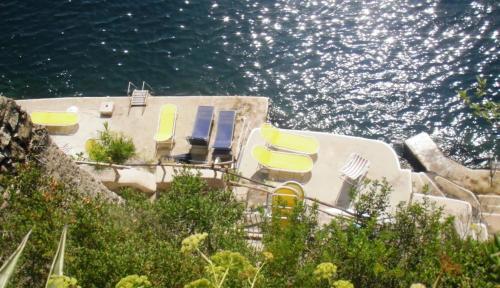 une maison avec des chaises jaunes et bleues et l'eau dans l'établissement Stella Marina Amalfi Dreams, à Ravello