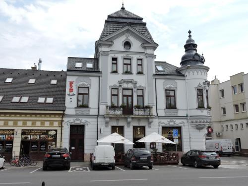 a white building with a clock tower on top of it at Olymp penzion in Komárno