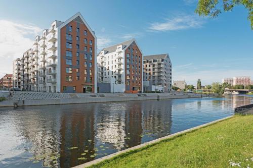 een rivier in een stad met hoge gebouwen en appartementen bij GRANO APARTMENTS Gdańsk Nowa Motława SPA & Wellness in Gdańsk