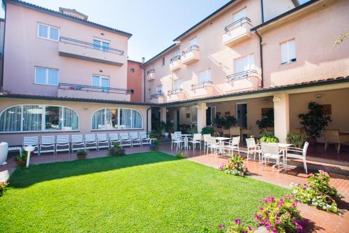 um pátio de um edifício com mesas e cadeiras em Hotel Sabrina em Castiglione della Pescaia