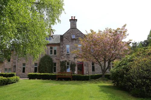 une ancienne maison en pierre avec un banc dans la cour dans l'établissement Carnach House, à Nairn