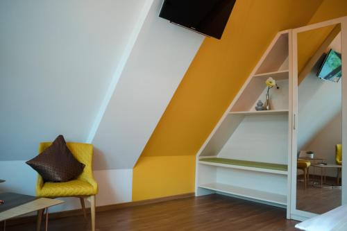 a room with a yellow chair and a book shelf at Altstadt-Apartment in Freiberg