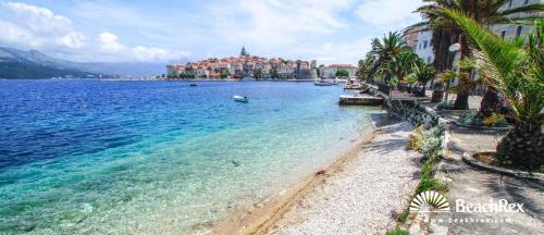 een strand met palmbomen en een stad op de achtergrond bij Apartments Jasmina in Korčula