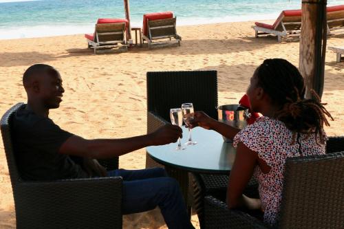 Un uomo e una donna seduti a un tavolo sulla spiaggia di Pure Plage a Lomé