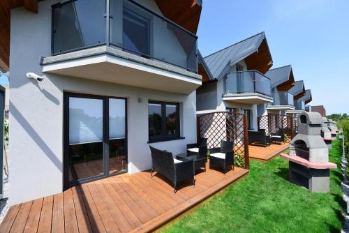 une maison avec une terrasse munie de chaises dans l'établissement Jastrzębia Marina - komfortowe całoroczne domki, à Jastrzębia Góra