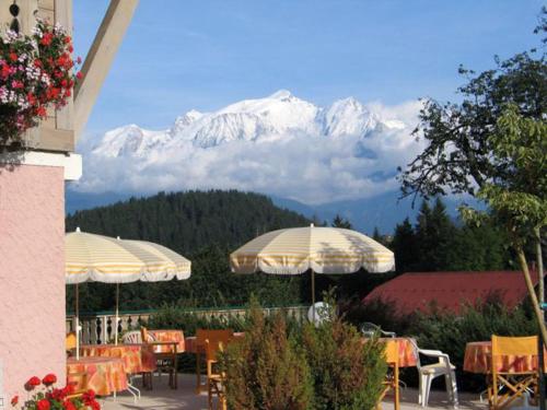 un restaurante con mesas y sombrillas frente a una montaña en Le Cordonant, en Cordon