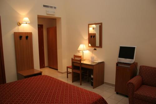 a hotel room with a bed and a desk and a television at Hotel Adria in Bari