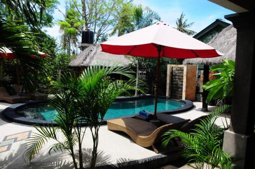 una piscina con sombrilla y sillas rojas, mesa y sombrilla en Gili Flush Harmony, en Gili Trawangan